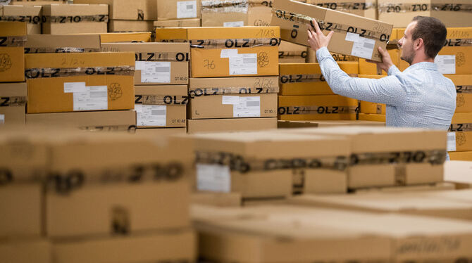 Ein Mitarbeiter von Olymp hat im Lager eine Kiste in der Hand. Die Zulieferer, mit denen Olymp zum Teil seit Jahrzehnten zusamm