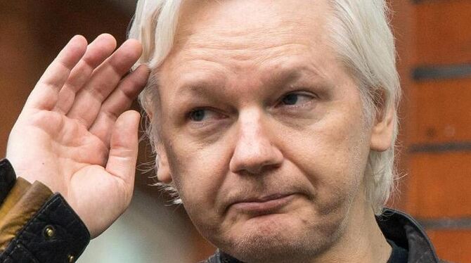Julian Assange grüßt mit der Hand