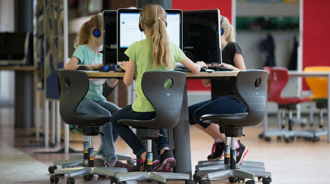 Schüler sitzen an einem Computer-Arbeitsplatz in einer Grundschule. Bei der Ausstattung mit Computern und schnellem Internet sch