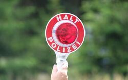 Eine Polizisten hält eine rote Winkerkelle in die Höhe