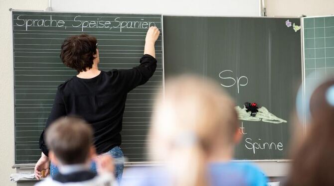 Eine Lehrerin schreibt in einer Schule an die Tafel