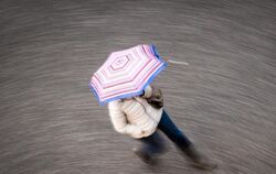 Eine Frau geht bei regnerischem Wetter über eine Straße