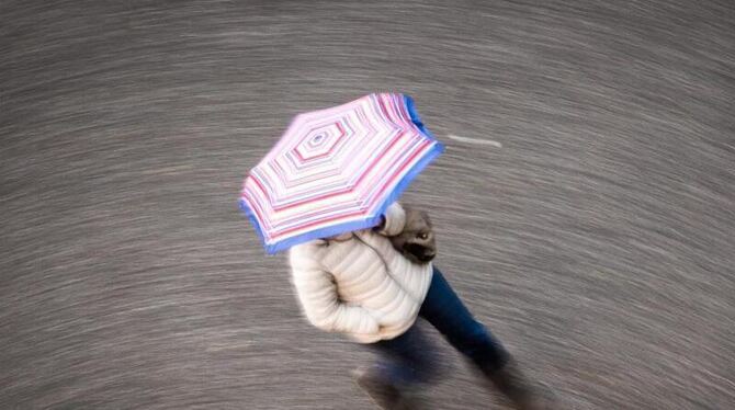 Eine Frau geht bei regnerischem Wetter über eine Straße