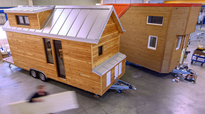 Ein Mitarbeiter trägt eine Holzplatte durch die Produktionshalle von Tiny House Wendland.