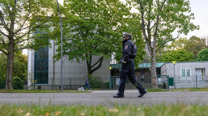 Ein Polizist patroulliert am Tag nach der Attacke auf der Straße vor dem Eingangsbereich der Hamburger Synagoge.  FOTO: WALZBERG
