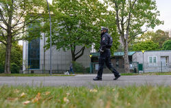 Ein Polizist patroulliert am Tag nach der Attacke auf der Straße vor dem Eingangsbereich der Hamburger Synagoge.  FOTO: WALZBERG