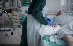 Eine Mitarbeiterin der Pflege in Schutzausrüstung betreut einen Corona-Patienten.   FOTO: STRAUCH/DPA