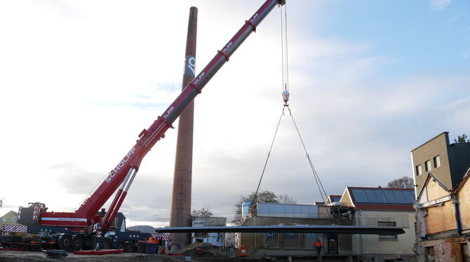Am Haken des Autokrans hängt die neue Ermsbrücke, die künftig das G & V-Gelände mit der Metzinger Innenstadt verbindet. FOTO: FI
