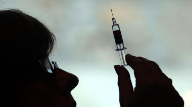 Eine Krankenschwester hält eine Spritze in die Höhe