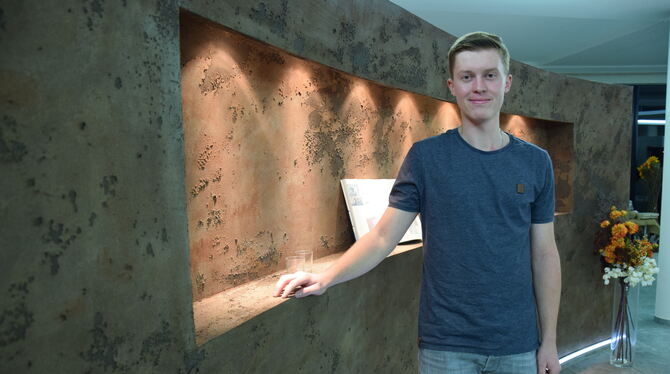 Marc Ebinger in den Räumen des elterlichen Betriebs vor einer Ausstellungswand, die in Rostoptik gestaltet wurde.  FOTO: SAUTTER