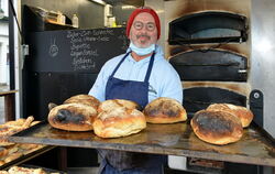 Vito Culjak in seiner mobilen Backstube auf dem Reutlinger Wochenmarkt: Er bedient den Ofen und die Kundschaft. FOTO: NIETHAMMER