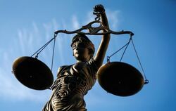 Eine Statue der Justitia hält eine Waage in ihrer Hand