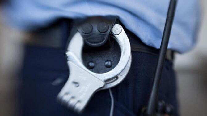 Handschellen hängen am Gürtel eines Justizbeamten
