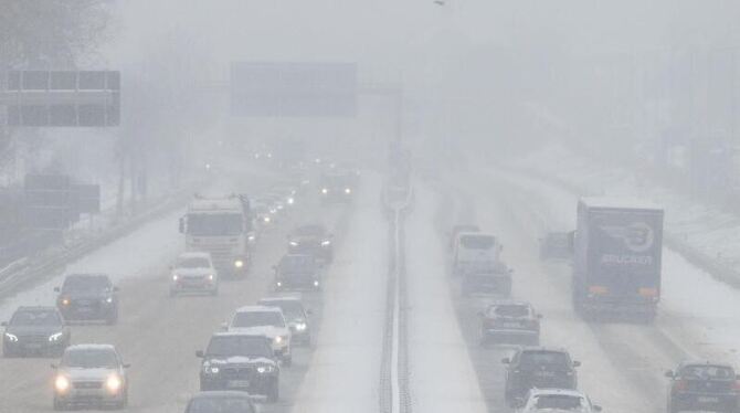 Autos fahren bei Nebel auf der mit Schnee bedeckten B10