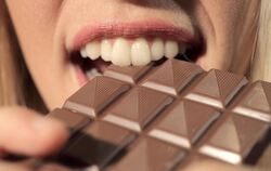 Eine Frau beißt in eine Schokolade.