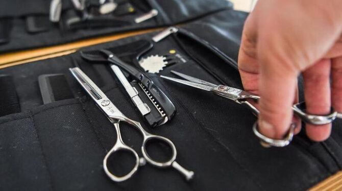 Eine Friseurin nimmt eine Haarschere aus ihrer Tasche Eine Friseurin nimmt eine Haarschere aus ihrer Tasche