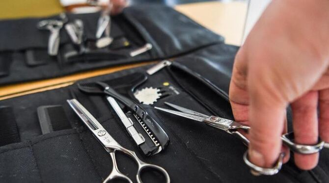 Eine Friseurin nimmt eine Haarschere aus ihrer Tasche Eine Friseurin nimmt eine Haarschere aus ihrer Tasche