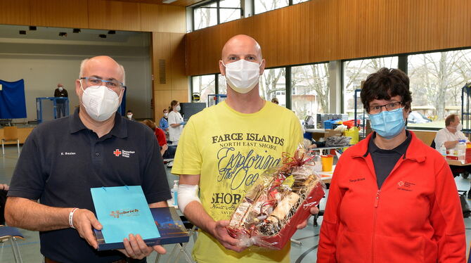 Den 25 000. Blutspender, Matthias Braun (Mitte) haben Eberhard Bazlen (links) und Tanja Braun in der Turnhalle in Öschingen geeh