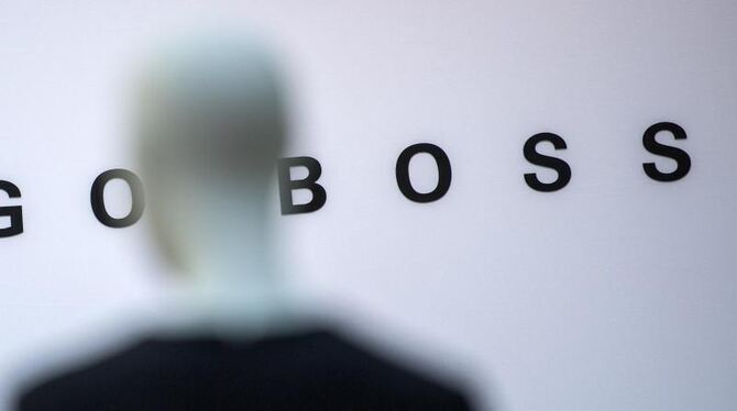 Eine Schaufensterpuppe steht vor dem Logo der Hugo Boss AG
