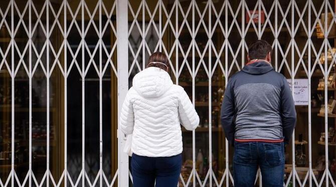 Zwei Passanten stehen vor einem geschlossenen Geschäft Zwei Passanten stehen vor einem geschlossenen Geschäft