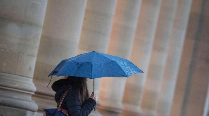 Eine Passantin geht bei Regen durch die Stadt Eine Passantin geht bei Regen durch die Stadt