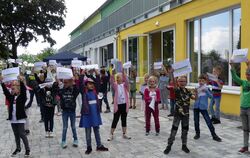 Grundschüler der Rulamanschule Grabenstetten halten stolz Schilder mit den neuen Schul-Logos hoch.  FOTO: SANDER