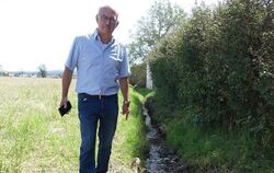 Roland Bengel zeigt auf den Graben, der bei Starkregen das Wasser aufnehmen soll. Etwas weiter hinten macht der Graben eine 90-G
