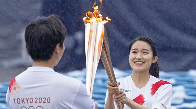 Japanische Läufer reichen das olympische Feuer von Fackel zu Fackel weiter. Doch Zuschauer sind beim olympischen Fackellauf hin