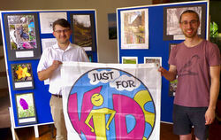 »Just for Kids«- Koordinator Florian Kern und Silas  Pfeifer von der Kulturwerkstatt mit dem Logo vor der Fotoausstellung, die a