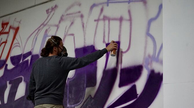 Ein Sprayer besprüht eine weiße Wand auf dem innoport-Gelände in Reutlingen.
