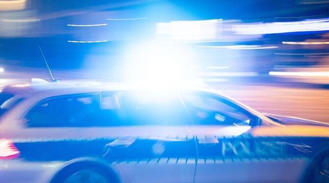 Ein Polizeiauto fährt mit Blaulicht über eine Straße