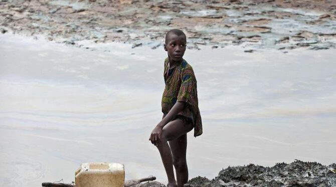 Ein Junge steht auf am ölverschmierten Ufer einer Bucht im Nigerdelta. Shell zahlt im Streit um ausgelaufenes Öl insgesamt 55