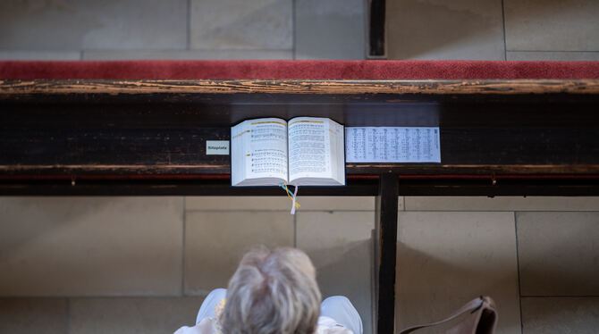 Eine Teilnehmerin hört in einer evangelischen Kirche während eines Sonntagsgottesdiensts der Predigt der Pfarrerin zu