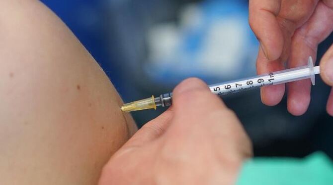 Ein medizinischer Mitarbeiter impft eine Frau