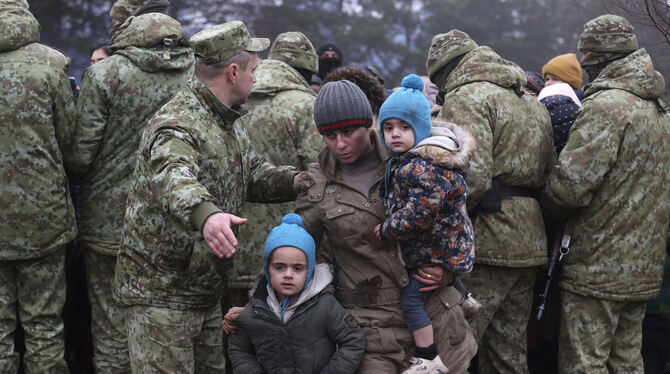 Ein Migrant mit Kindern wird an der belarussisch-polnischen Grenze von einem Soldaten weitergewunken. FOTO: MANCHUK/DPA