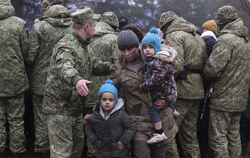 Ein Migrant mit Kindern wird an der belarussisch-polnischen Grenze von einem Soldaten weitergewunken. FOTO: MANCHUK/DPA