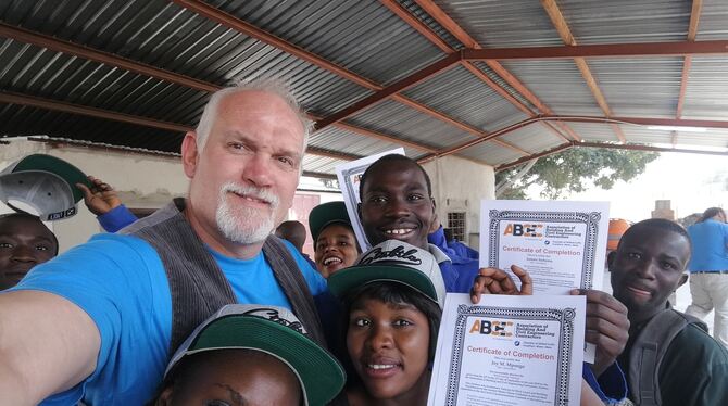 Carsten Pabst zusammen mit den Kursteilnehmern und -teilnehmerinnen in Sambia. Stolz zeigen sie das bei ihm erworbene Zertifikat