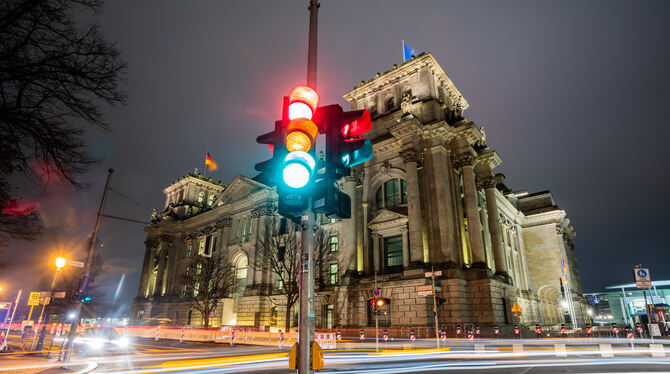 Eine Ampel leuchtet in einer Aufnahme mit Langzeitbelichtung am Morgen vor dem Reichstagsgebäude in allen drei Phasen.