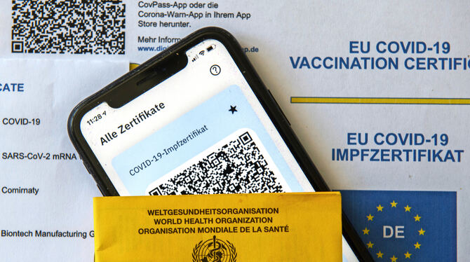 Ein Impfpass und ein Smartphone, auf dem die App CovPass läuft.