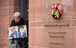 Die Syrerin Fadwa Mahmoud kommt aus dem Gebäude des Koblenzer Oberlandesgerichts und hält ein Bild ihres Partners und ihres Sohn