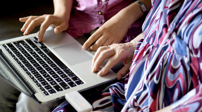 Die Hände einer jungen Frau und einer Seniorin berühren einen Rechner. Zusammengebracht hat die beiden in Hannover Lebenden das