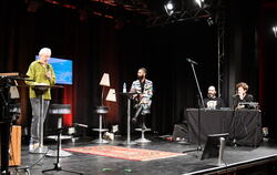 Auf der Bühne von links, stehend: Moderator Peter Elwert, daneben Dave E. Rämm, am Pult mit Bart Marcus Prest und Stefan Grabows