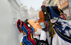 Zwei Rottweiler Narren mit OP-Masken über dem Gesicht küssen sich im Februar 2021.
