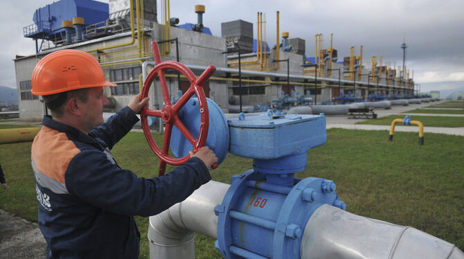 Gashahn zu oder auf? Ein Arbeiter dreht an einem roten Rad an der Erdgasverdichterstation.  FOTO: PALAMARCHUK/DPA