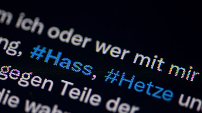 Auf dem Bildschirm eines Smartphones sieht man die Hashtags Hass und Hetze in einem Twitter-Post.