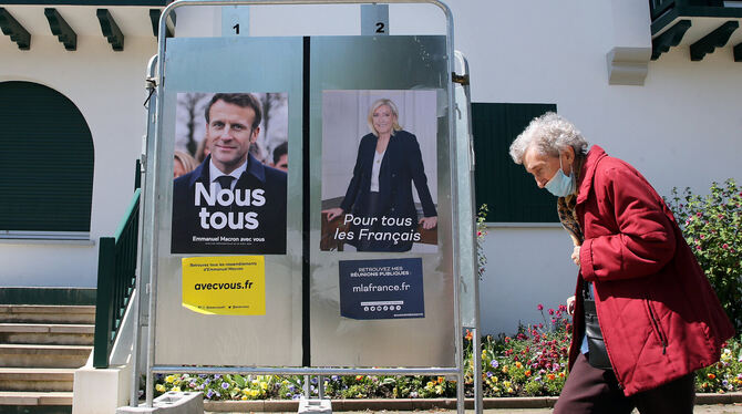 Eine Frau geht an Wahlkampfplakaten der französischen Präsidentschaftskandidaten Emmanuel Macron und Marine Le Pen vorbei.  FOTO