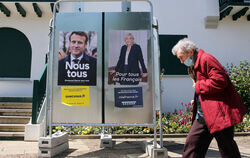 Eine Frau geht an Wahlkampfplakaten der französischen Präsidentschaftskandidaten Emmanuel Macron und Marine Le Pen vorbei.  FOTO