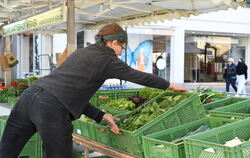Christine vom Bioland Gärtnerhof Werner räumt eine Kiste frischen Spinat auf den Marktstand. 