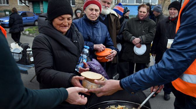 Anwohner stehen im ukrainischen Ort Butscha bei der Essensausgabe an.  FOTO: GUZY/DPA