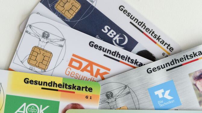 Gesundheitskarten verschiedener Krankenkassen liegen auf einem Tisch.
